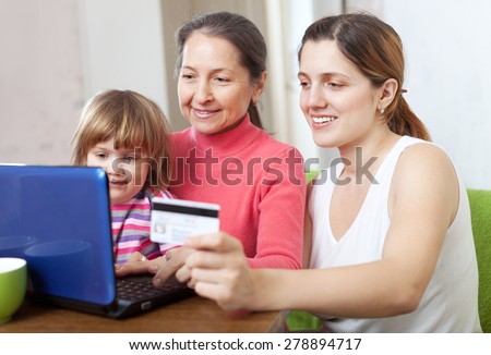Woman with mother and child with laptop, paying by credit card in internet store