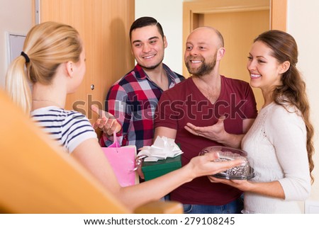 Cheerful smiling happy guests with presents and cake standing in doorway. Focus on girl