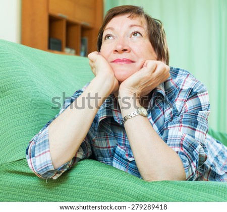 Stressed elderly female laying on her elbows and thinking indoor