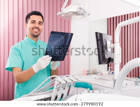 Smiling male dentist looking x-ray scan