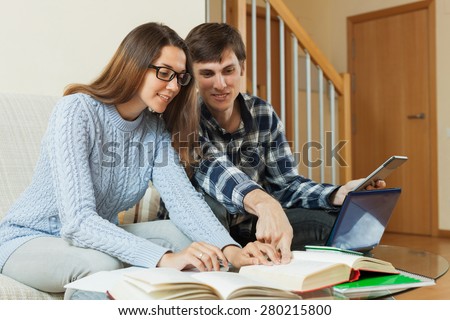Young student couple sitting on the sofa and preparing for exam