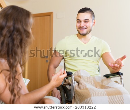 Handsome handicapped man  in wheelchair and his  girlfriend 20-25 years old having conversation