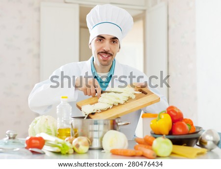 cheerful caucasian cook in white uniform does veggy lunch