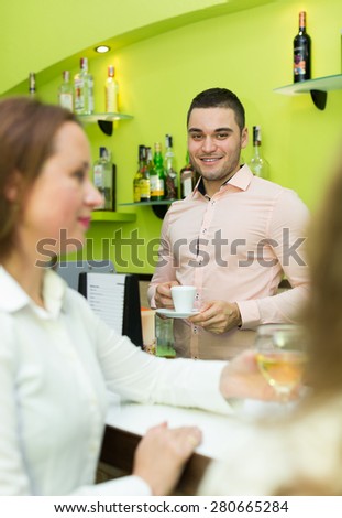 Two beautiful female friends chatting and drinking wine at the bar