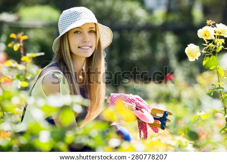 Smiling  gardener in uniform working in roses plant