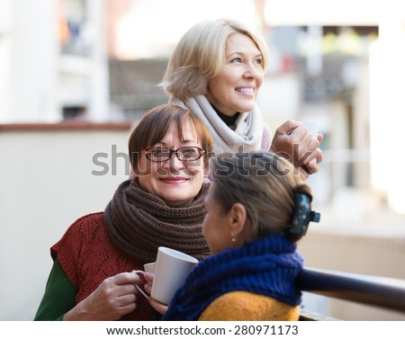 Portrait of cheerful female pensioner friends drinking coffee at patio. Focus on brunette