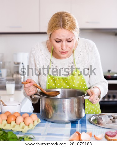 Unhappy woman preparing exotic food with rank odour at kitchen