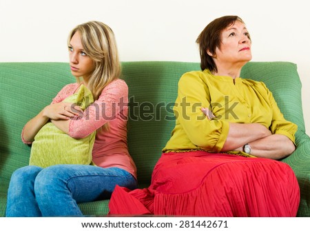 Sad mature mother and adult daughter after conflict  in home interior