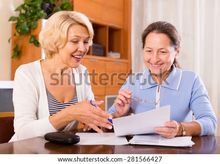 Cheerful female pensioners discussing contracts indoor.Focus on the woman on the left