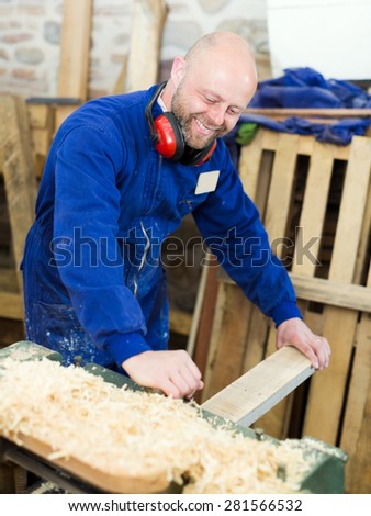 portrait cheerful male worker on lathe at  wood workroom