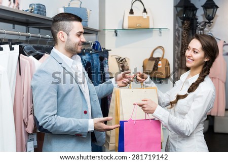 Smiling male customer with cheerful female shop assistant at boutique. Focus on man