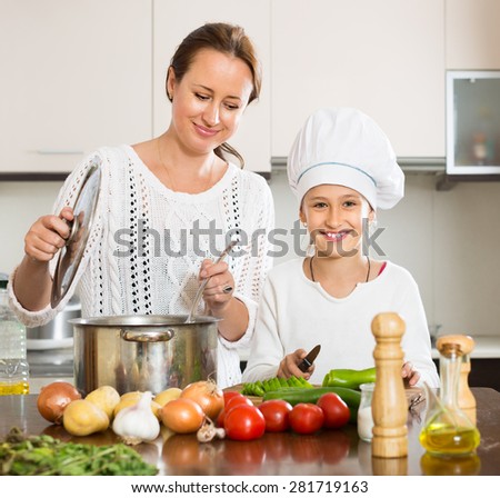 Portrait of smiling girl and mom with vegetables and casserole at domestic kitchen