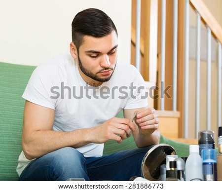 Young handsome guy doing manicure in home interior