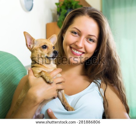 Happy girl holding Russkiy Toy Terrier indoor