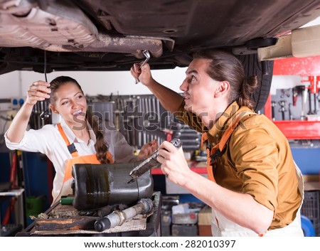 Happy mechanics crew repairing a broken car at auto service center