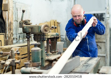 concentrated adult male worker on lathe at  wood workroom