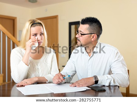 Upset spouses having financial problems. Sad wife and husband sitting at the table and looking at a pile of documents