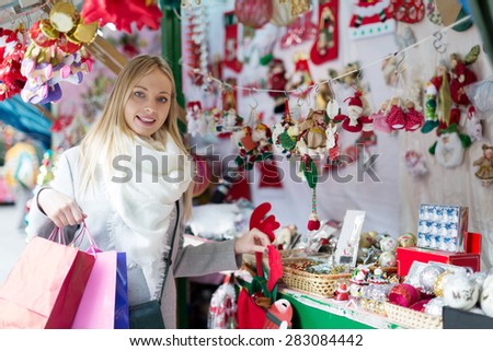 cheerful young  girl shopping at festive fair before Xmas at Christmas market