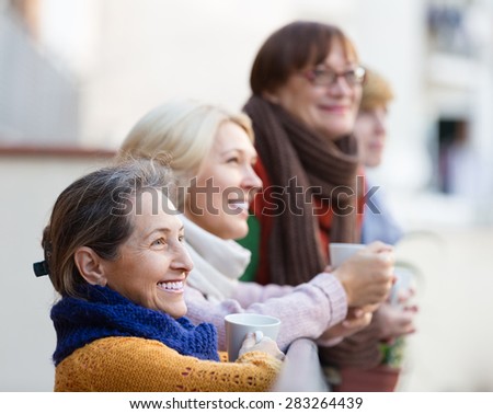 Group of smiling senior female friends drinking tea at balcony