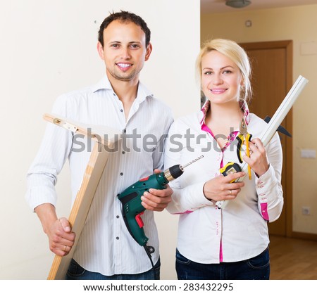 Happy young man and woman choosing place for shelf at home