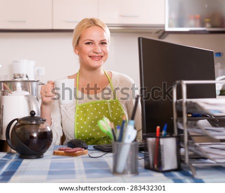 caucasian female freelancer with PC, tea and sandwich at kitchen table