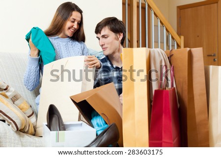 Young woman and man shopaholic smiling with shopping bags in home