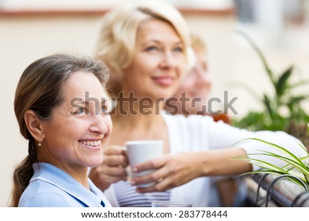 Happy elderly female colleagues having lunch break at patio and drinking tea