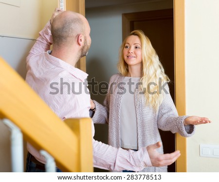 Adult man standing at his hall and inviting girlfriend to come inside