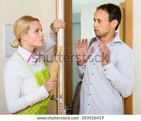 Angry serious woman threatens with rolling-pin for a frightened man