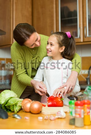 Portrait of smiling girl and mom with raw vegetables and casserole