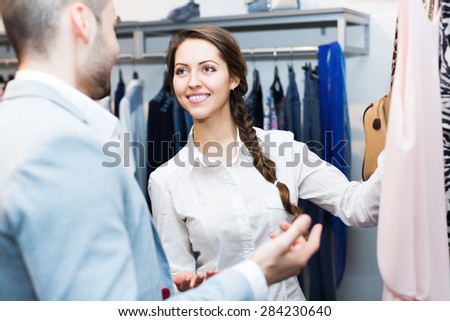 Store clerk serving cheerful purchaser at fashionable apparel store