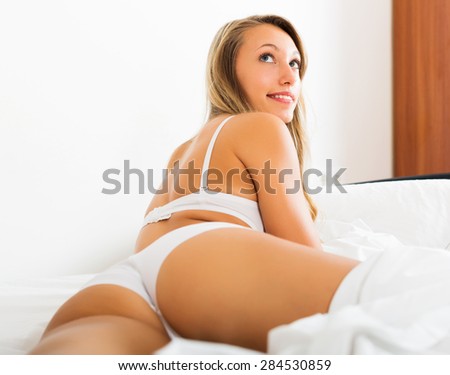 Sexy blonde long-haired woman in underwear posing on bed at bedroom