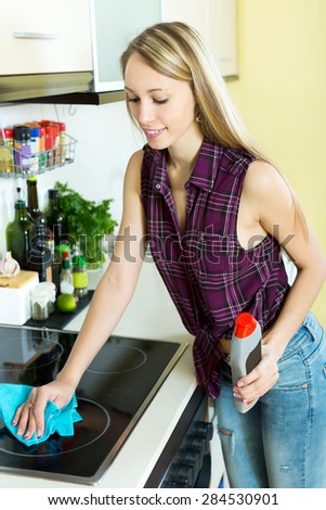 happy young maid cleans modern stove cleaner at home