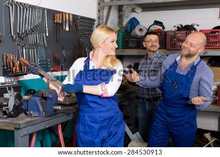 two happy workers and adult superviser at auto repair shop. Focus on the woman