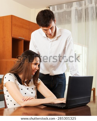 Ordinary couple with notebook at table at home. Focus on woman