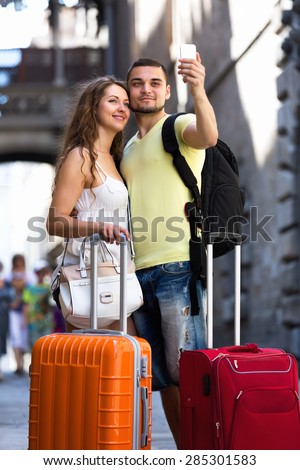 Man and woman with luggage doing selfie during city tour