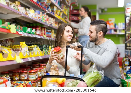Young positive family purchasing food for week at supermarket