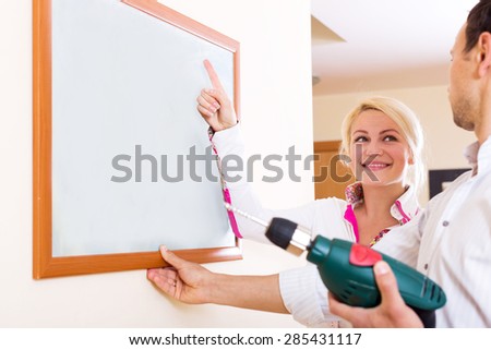 Cheerful young couple drilling Wall to Hang picture frame