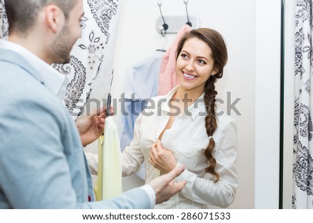 Portrait of cheerful young couple with new apparel at fitting-room in clothing store