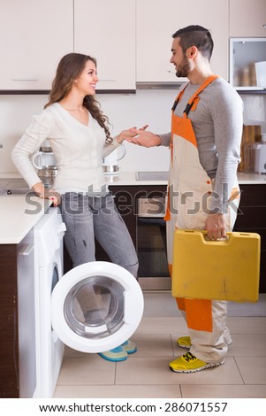 Female client and warranty service man near washing machine at kitchen
