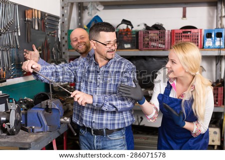 Portrait of auto service center crew with young smiling blonde near tools and equipment. Selective focus