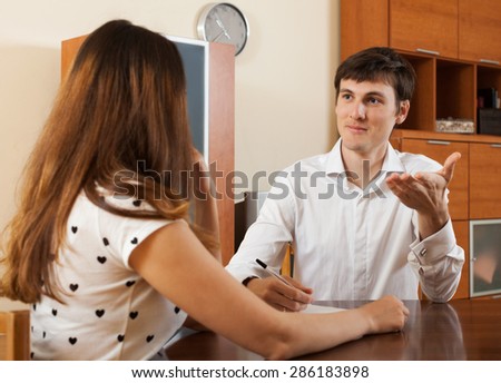 Young woman with real estate agent signing agreement at home