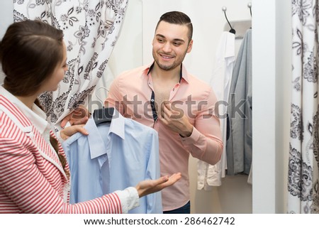 Portrait of positive smiling young couple at fitting-room in clothing store