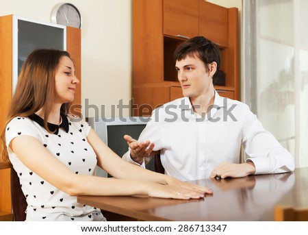 Casual young couple having serious talking at table in  room