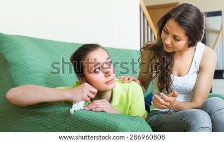 Young longhaired woman calms a crying friend at home