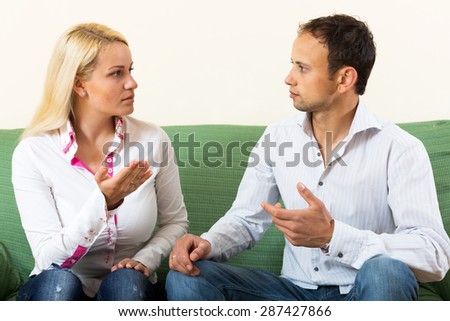 Serious adult couple talking in home interior