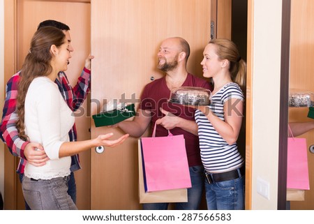 Cheerful smiling guests with presents and cake standing in doorway. Focus on girl