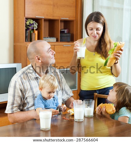 happy  family of four eating sandwiches at home interior