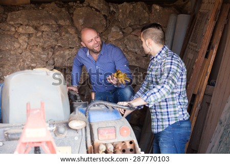 Smiling russian mechanics reparing old agrimotors at farm