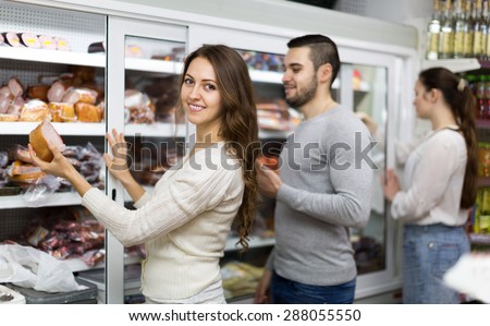 Happy customers standing near fridge with meat products